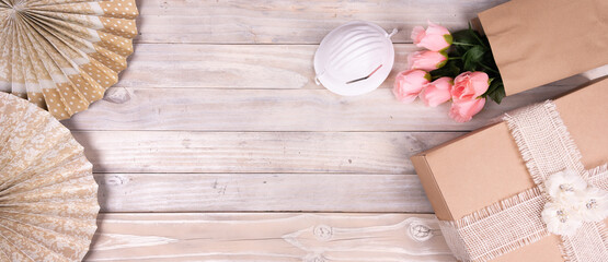 Celebration,party backgrounds concepts ideas, with pink flowers, gift box and face mask over wooden background. Top view