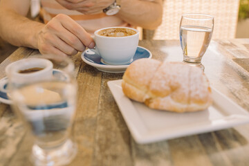 Breakfast with croissant and coffee on summer terrace on sunny day.
