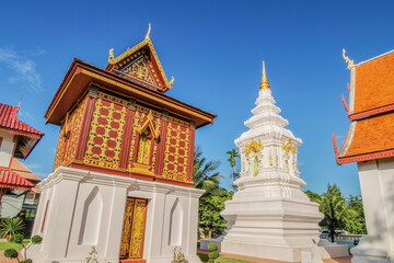 view of ancient traditional Hor Kham Luang and white Chedi with blue sky background, Wat Hua Khuang, Nan Province, northern of Thailand.