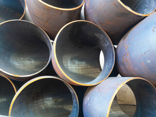 Withdrawal for industrial metal pipes at a right angle on the concrete floor. Curved rusty metal...