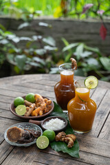 Herbal drinks of beras kencur and kunyit asam are packed in glass bottles,raw materials of white rice,rhizomes of kencur,turmeric,brown sugar,tamarind and oranges for garnishes