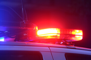 Flashing emergency lights at night. They are red and on the top of a first responders vehicle. © Rose Makin