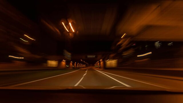 Hyperlapse of a tunnel drive with a car, front view through the windshield with speed blurry effects.