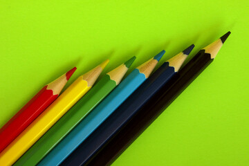 Colored pencils on a green background. Lots of different colored pencils. Colorful pencil. Close. Pencils are sharp. Pencils lie diagonally in the lower left corner. Copy space. Background. Fiat lay