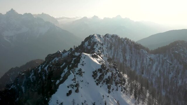 Camera following the ridge line of Srednji Vrh looking towards Kranjska Gora and Triglav National Park. Aerial view of the Karavanke Alps in the winter on a clear skies day.