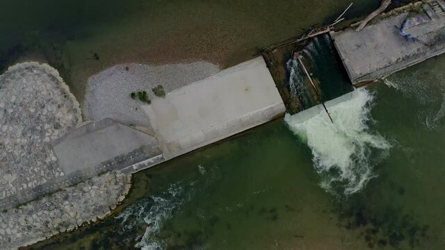 Top view at a little dam of Munichs Isar river, then rising up with the drone including a camera swing up to the popular buildings of the bavarian capital e.g. the Frauenkirche.