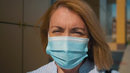 Antivirus protection. A woman in a protective surgical face mask walks down the street alone. Quarantine, pandemic, no-man's land. - Powered by Adobe