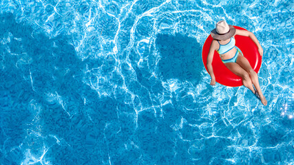 Active young girl in swimming pool aerial top view from above, child relaxes and swims on...