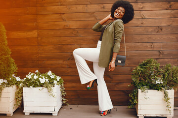 Fashionable girl in a summer city. Black lady in a green jacket