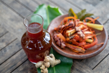 red herbal drinks and raw materials in a pottery plate on a wooden table