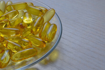 Fish oil capsules on a glass plate. A lot of vitamin omega 3. Close-up.