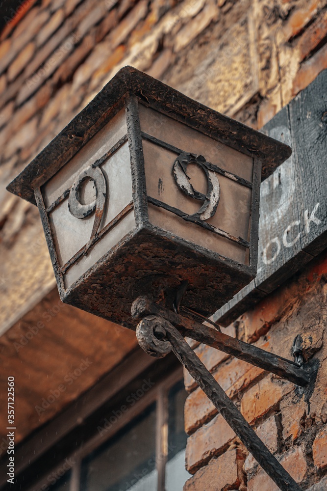 Poster Low angle vertical shot of an old wall lamp with a block number nine