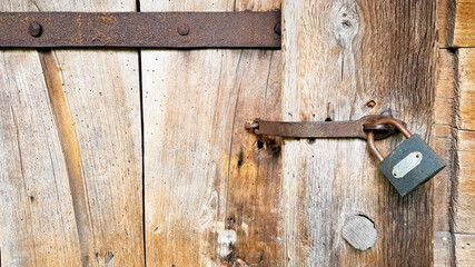 Old vintage metal padlock on a closed wooden door of an old farmhouse. The true style of the village. close-up. focus on the castle. Wooden background, texture. Copy space