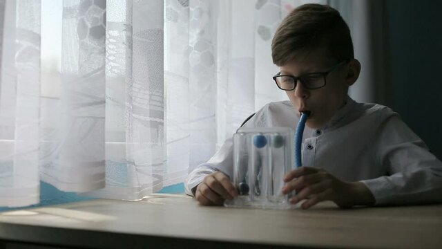 Young caucasian boy deep breathing exercise with spirometer.  Respiratory exerciser for help perform normal deep breathing