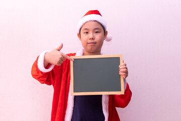 Asian boy in Santa Claus clothes holding empty board. Merry christmas