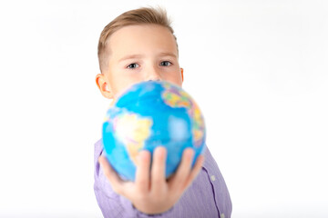 Playful young caucasian school boy holding a globe on white studio background.Boy is surprised shows at globe laughing