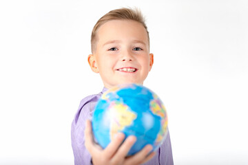 Playful young caucasian school boy holding a globe on white studio background.Boy is surprised shows at globe laughing