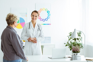 Smiling diet expert welcoming a patient with diabetes in modern and bright office with laptop, lamp and plants