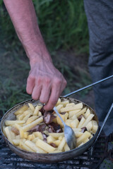 A man tries fried potatoes in a pan.