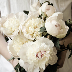 Beautiful bouquet of white peonies in hands