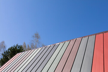 Fototapeta na wymiar Colorful roof of a single-family house. Blue clear sky during spring morning.