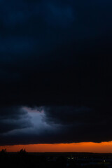 Black thunderclouds at sunset. Bright orange sunset and dark clouds. Storm sky