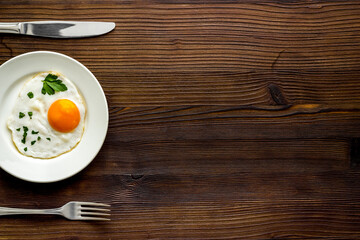 Fried eggs on plate - dark wooden dinner table from above copy space