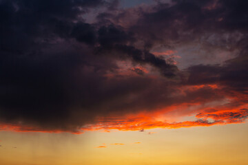 Fototapeta premium Black thunderclouds at sunset. Bright orange sunset and dark clouds. Storm sky