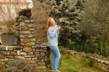 girl drinks tea in morning in yard near stone well of village house in Provence.