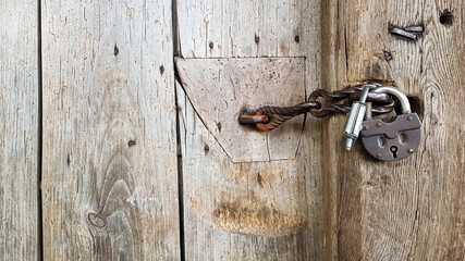 Old vintage metal padlock on a closed wooden door of an old farmhouse. The true style of the village. close-up. focus on the castle. Wooden background, texture. Copy space