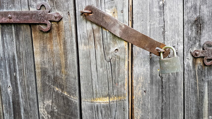 Old vintage metal padlock on a closed wooden door of an old farmhouse. The true style of the village. close-up. focus on the castle. Wooden background, texture. Copy space