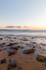 Water flowing around the rocks on the sand.