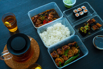 Asian food, sushi, rolls, rice and chicken skewers. Food in disposable dishes. Order Asian Food at Home