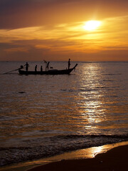 silhouette unidentified local fisherman go fishing by small traditional long tail boat in evening time with sunset