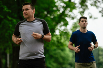 Young men training on a race track. Two young friends running on athletics track 