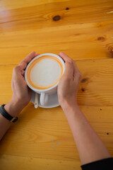 Hand Women put a Latte arts coffe hot coffee on wooden table.barista love art concept.