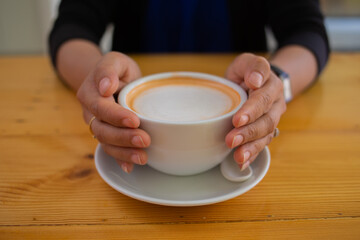 Hand Women put a Latte arts coffe hot coffee on wooden table.barista love art concept.