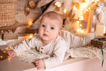 Fototapeta premium A small baby in light clothing lies on the background of the Christmas decor.