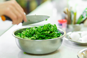 Cook in the kitchen cuts greens close up