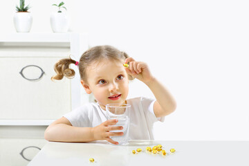 a child looks at a capsule omega3 takes pills, yellow capsules