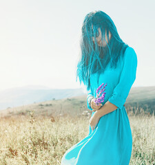 Woman in blue dress walking in summer meadow.