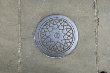 round manhole cover on the street, decorated with a star pattern