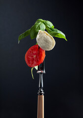 Mozzarella with tomato and basil on a fork.