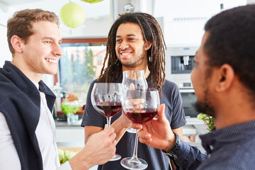 Freunde beim Anstoßen mit Glas Rotwein in der Küche