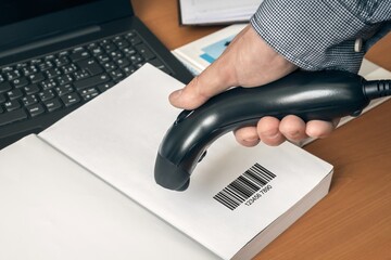 Man with scanner scans barcode in a book