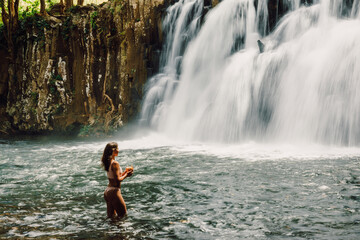 Rochester Falls and sexy woman in bikini. Amazing cascade waterfall in Mauritius