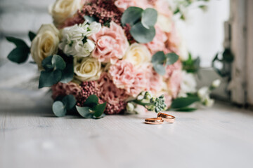 wedding rings lie on the background of a wedding bouquet with pale pink flowers