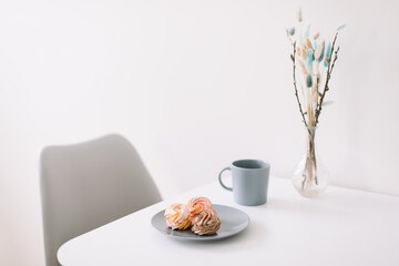 Cup of coffee with marshmallows and flowers on the table. Romantic morning. Tasty breakfast. Flat lay, top view, copy space.