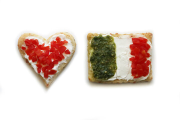 Salad cookies in shape of red heart and italian flag isolated on white background. Snack with tradional italian ingredient: pesto, cheese and red tomatoes

