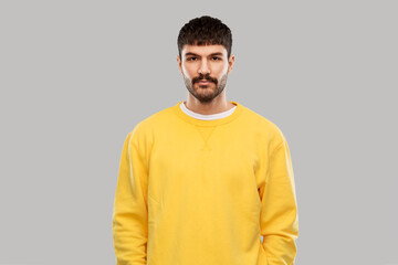 people concept - young man in yellow sweatshirt over grey background